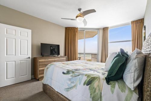 a bedroom with a bed and a tv and a window at Emerald Dolphin 0640 in Pensacola Beach