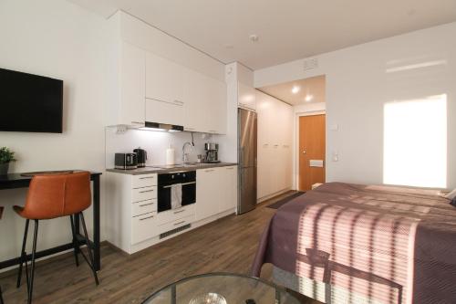 a bedroom with a bed and a table and a kitchen at City Apartment Aapelintupa in Kuopio