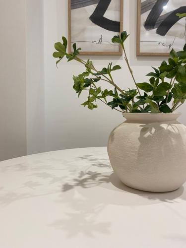 a white vase sitting on a table with a plant at Smart Stay Córdoba in Córdoba