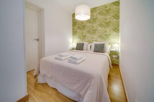 Un dormitorio con una cama blanca con toallas. en Encantador apartamento con patio, en Málaga