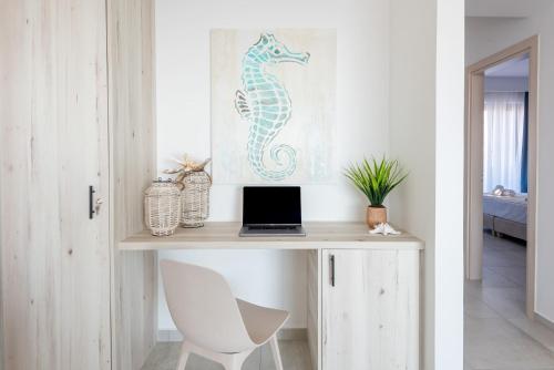 a desk with a seahorse picture and a laptop on it at Aquarama Pool Apartments in Ixia