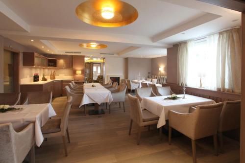 a restaurant with white tables and chairs and a kitchen at Hotel Kaiserhof in Medebach
