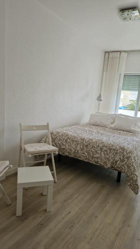a bedroom with a bed and a chair and a window at Casinhas da Praia in São Martinho do Porto
