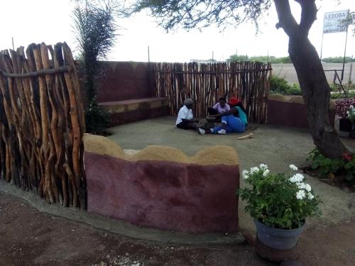 three people sitting on the ground next to a fence at Ledoba Bed & Breakfast in Molalatau