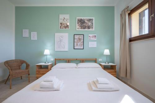 1 Schlafzimmer mit einem großen weißen Bett und 2 Stühlen in der Unterkunft Agriturismo Terre di Castiglione in Castiglione della Pescaia