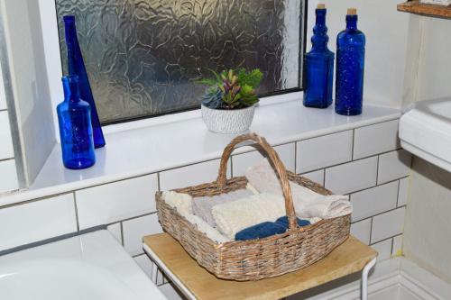 a basket sitting on a window sill with blue bottles at Beval Cottage in Abergavenny