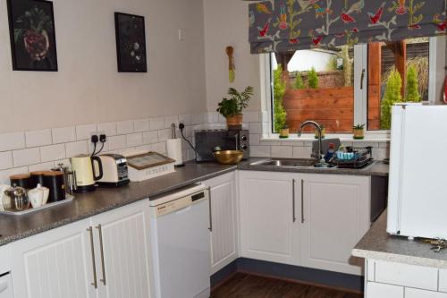 a kitchen with white cabinets and a sink at Beval Cottage in Abergavenny