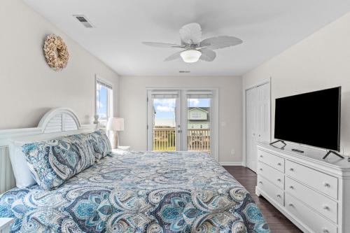 1 dormitorio con 1 cama y TV de pantalla plana en Sea Cloud, en Holden Beach