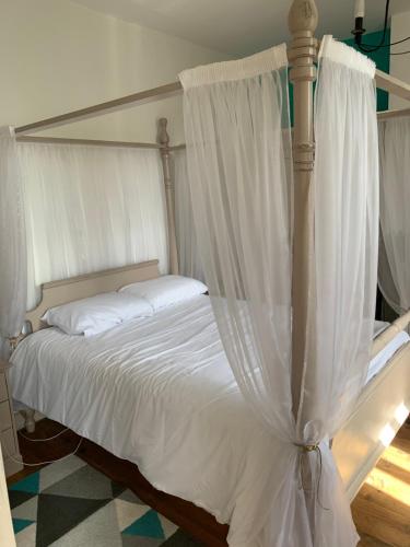 a bedroom with a canopy bed with white sheets at Lauberge de Nogaro in Caupenne-dʼArmagnac