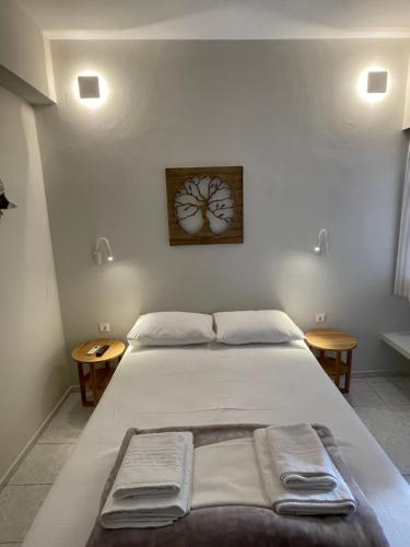a bedroom with a large white bed with two tables at Manto Apartments in Tinos Town