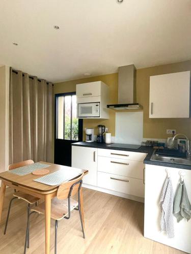 Il comprend une cuisine avec une table en bois et des placards blancs. dans l'établissement Au Petit Manoir, à Montbert