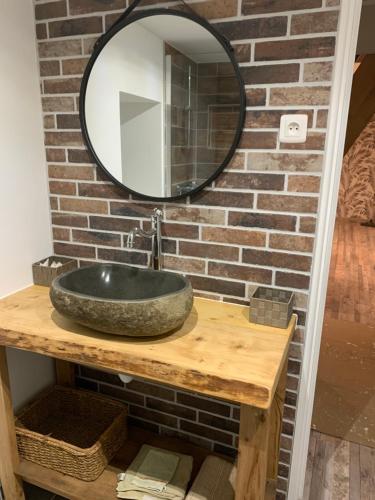 um lavatório de casa de banho com um espelho numa parede de tijolos em Chambre d’hôtes coconing em Brélès
