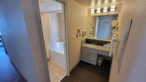 a bathroom with a sink and a mirror and a tub at Four Sails Resort in Virginia Beach