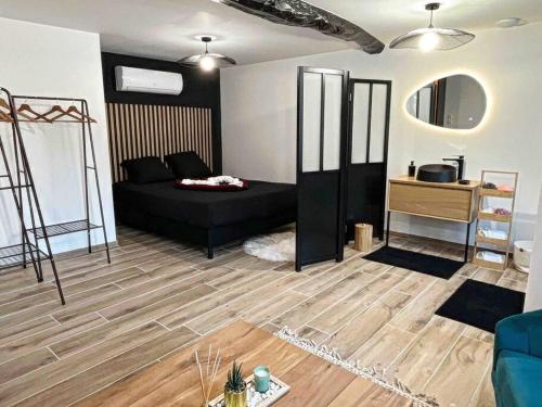 uma sala de estar com uma cama preta e piso em madeira em L’insolite airbnb em Vignieu