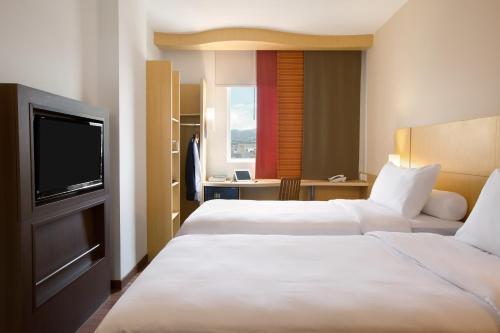 a hotel room with two beds and a flat screen tv at Ibis Bandung Pasteur in Bandung