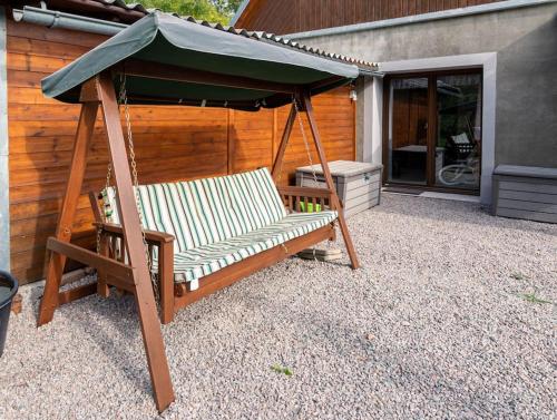 a swing with a green umbrella on a patio at Apartmán v podzámčí in Rychnov nad Kněžnou