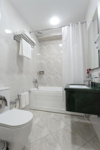 a white bathroom with a tub and a toilet and a sink at WELLFORT HOTEL in Samarkand