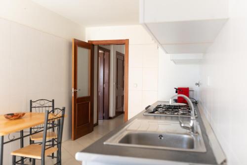 a small kitchen with a sink and a table at 2 bdr cozy beachside apartment, Copacabana - LCGR in Mindelo