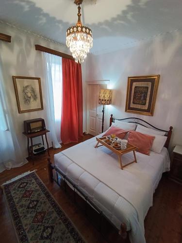 1 dormitorio con 1 cama grande y lámpara de araña en Vintage & Art apartment, en Corfú