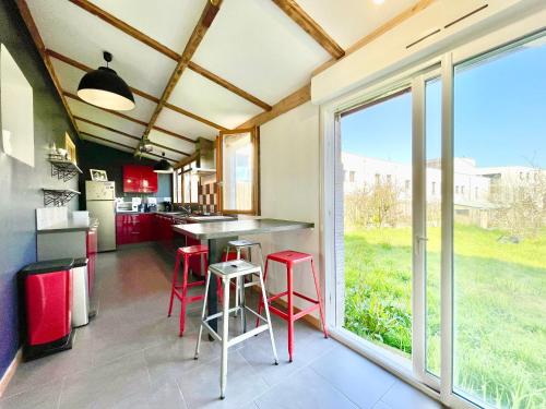 une cuisine avec tabourets rouges et une grande fenêtre dans l'établissement Pop House - Grand Jardin clos - BBQ - Spacieux & Lumineux, à Saint-Nazaire