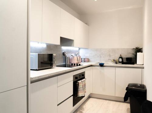 uma cozinha branca com armários e electrodomésticos brancos em Exquisite- stylish- luxurious 2 bed apartment em The Hyde