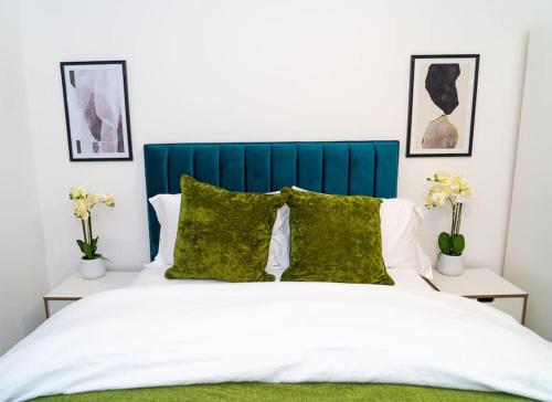 uma cama com cabeceira azul e almofadas verdes em Exquisite- stylish- luxurious 2 bed apartment em The Hyde