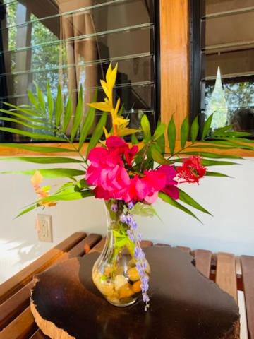 a glass vase filled with flowers on a table at Mariposa Jungle Lodge in San Ignacio