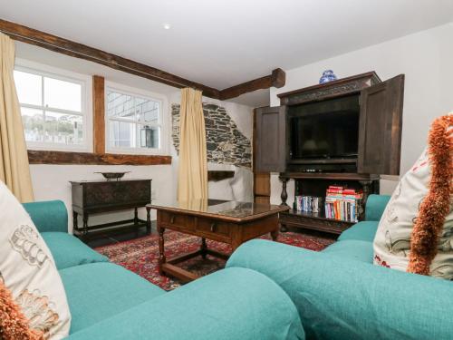 a living room with a blue couch and a tv at Glanville House in Mevagissey