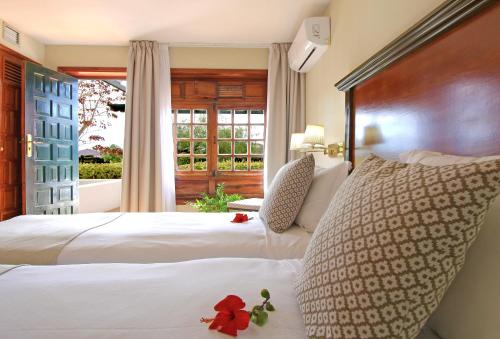 een slaapkamer met 2 witte bedden en een raam bij Hotel Rural Finca de La Florida in San Bartolomé