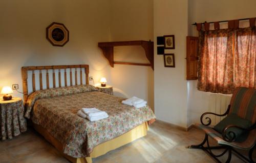 BarrandaにあるCasa Rural - Vuelta del Carrilのベッドルーム1室(ベッド1台、椅子、ランプ2つ付)