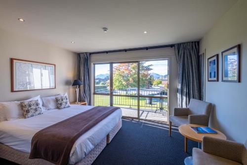 een hotelkamer met een bed en een groot raam bij Oakridge Resort Lake Wanaka in Wanaka