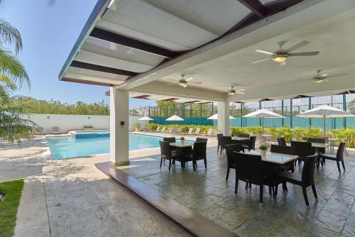 a patio with tables and chairs and a pool at Elegante Blue Marine Apartamento Juan Dolio in Juan Dolio