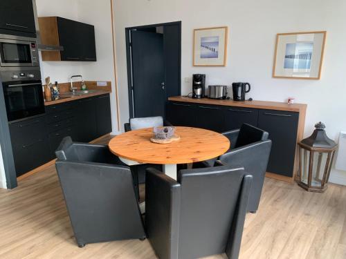 une cuisine avec une table en bois et des armoires noires dans l'établissement Appartement LE TRITON, à Perros-Guirec