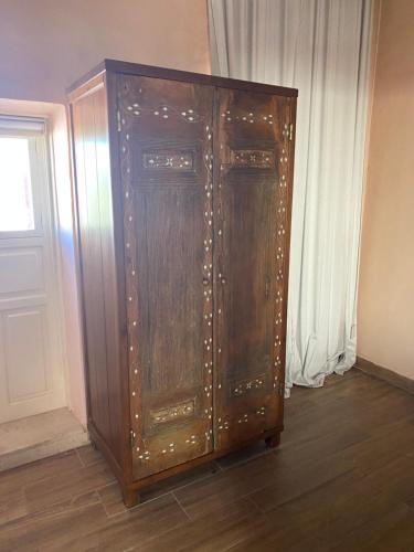 a large wooden cabinet in a room with a window at Dar Camelia in Soûr