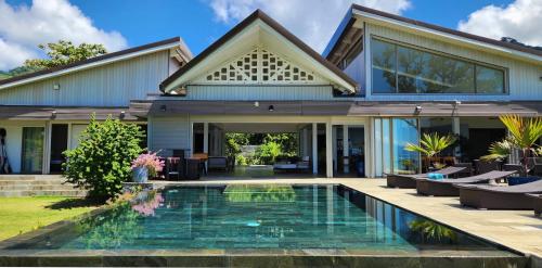 a house with a swimming pool in front of a house at Villa Jessivia in Afareaitu