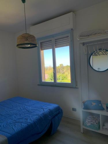 Un dormitorio con una cama azul y una ventana en Oasi verde con terrazza sul mare e con piscina, en Castiglioncello