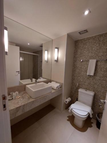uma casa de banho com um WC branco e um lavatório. em Mar Premier Flats Queimados em Queimados