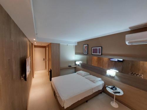 um quarto de hotel com uma cama e uma televisão em Mar Premier Flats Queimados em Queimados