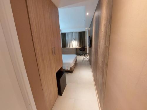 um corredor que leva a um quarto com uma cama e uma janela em Mar Premier Flats Queimados em Queimados