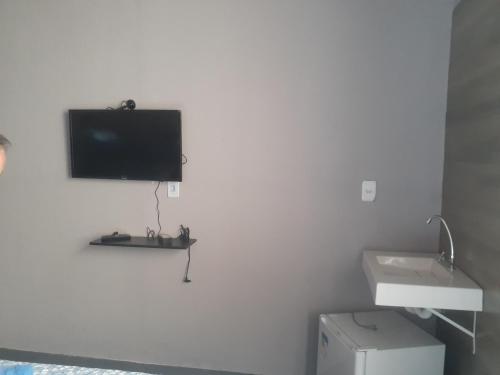 uma casa de banho com uma televisão numa parede branca em POUSADA ONDA CARIOCA em Cabo Frio