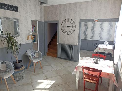 una habitación con mesas y sillas y un reloj en la pared en Chez Marie en Drosnay