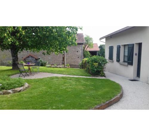 a small yard with a table and a house at Chambre d'hôtes à la campagne in Saint-Gence