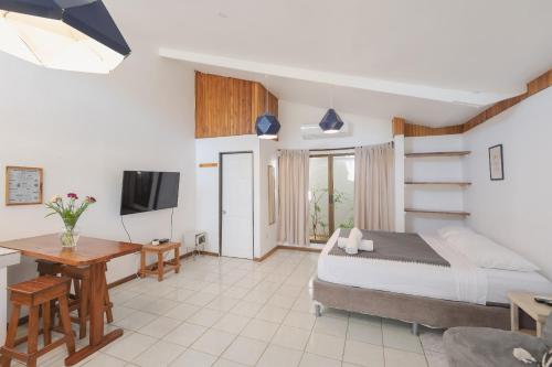 a bedroom with a bed and a desk and a television at Maoritsio Garden Studios in Santa Teresa Beach