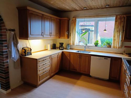 a kitchen with wooden cabinets and a sink and a window at Svendborg, Thurø ferievilla in Svendborg