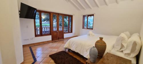 a bedroom with a bed and a tv and windows at CASONA DE LOS VIRREYES in Villa de Leyva