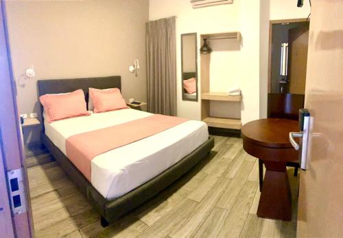 a bedroom with a bed with pink pillows and a table at Hotel Yivinaca in Barranquilla