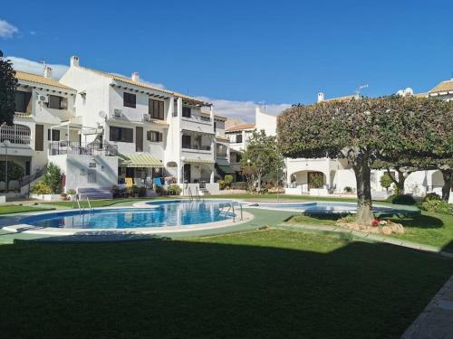 ein Schwimmbad in der Mitte eines Gartens mit Häusern in der Unterkunft Oleza Garden Village , Apartment Ines in Playa Flamenca