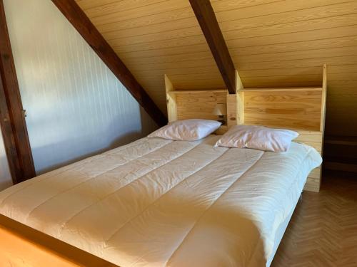 a bed with two pillows on it in a room at Chaleureux chalet en bord de mer in Merville-Franceville-Plage
