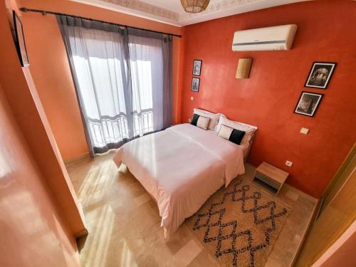 1 dormitorio con pared de color naranja, cama y ventana en Bright Apt in the Heart of Marrakech-Walk Everywhere en Marrakech