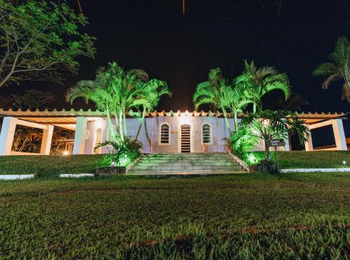 una casa blanca con palmeras por la noche en Hotel Fazenda Bona Espero, en Alto Paraíso de Goiás